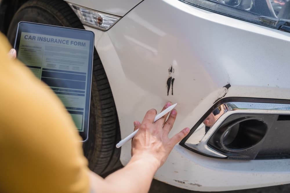 Insurance Adjuster examining damages of car