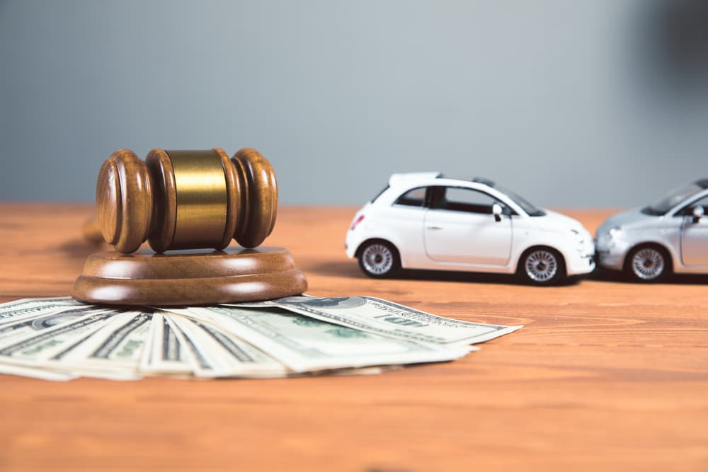 Judicial gavel with money and car on a wooden table